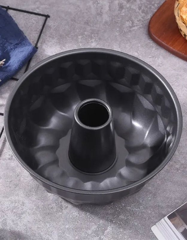 Black Bundt cake pan on a gray surface.
Black nonstick bundt cake pan with center tube for baking.